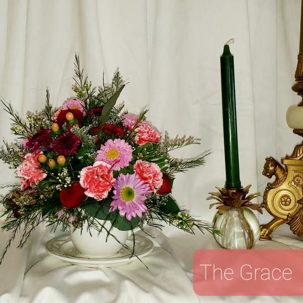 Mixed bouquet in a white bowl with a green candle beside it