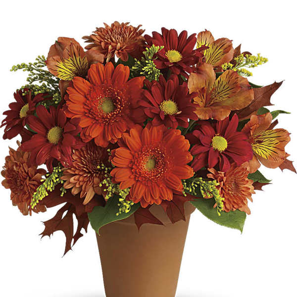 Orange and red mixed flower arrangement in a brown pot