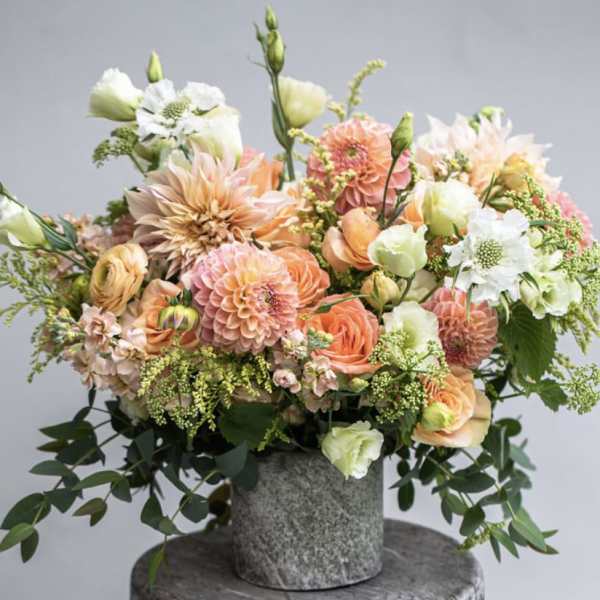 Peach and white mixed flower arrangement in a gray vase
