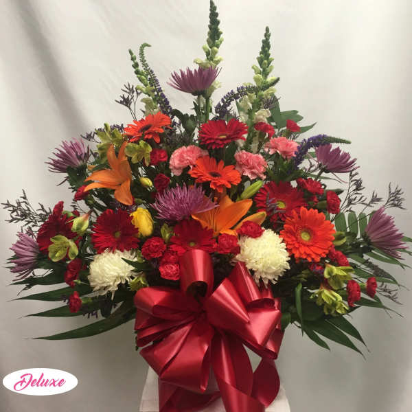 Large mixed bouquet with gerbera daisies, lilies, and a red ribbon bow