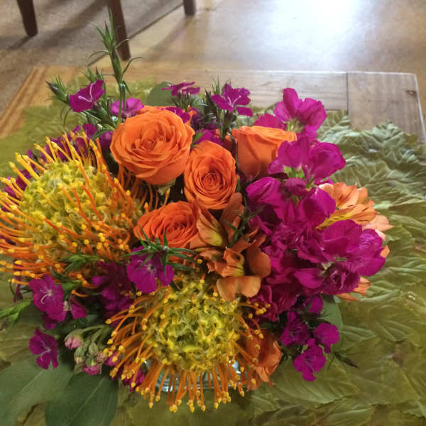 Bouquet of orange roses and magenta flowers on green leaves