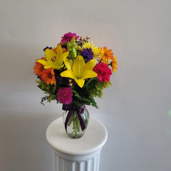 Colorful bouquet of lilies, daisies, and carnations in a glass vase