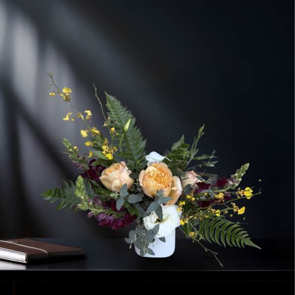 Peach and white roses in a white vase with yellow accent flowers