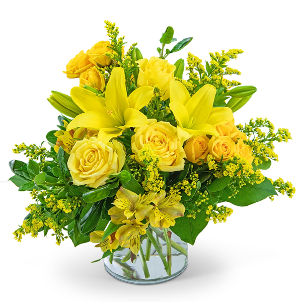 Yellow roses and lilies arranged in a clear glass vase