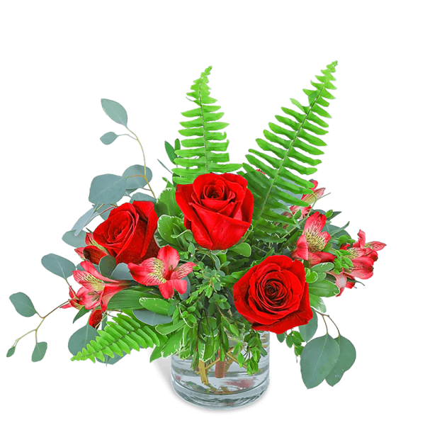 Red roses and pink flowers in a clear glass vase