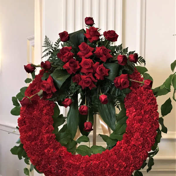 Red rose and carnation funeral wreath on an easel