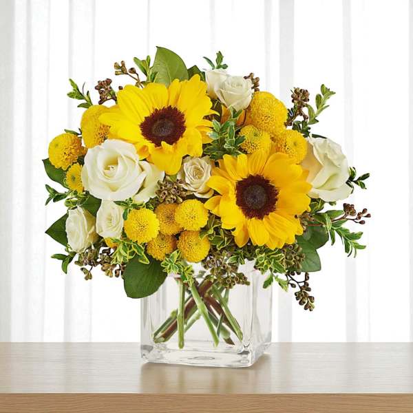 Sunflower and white rose bouquet in a clear glass vase