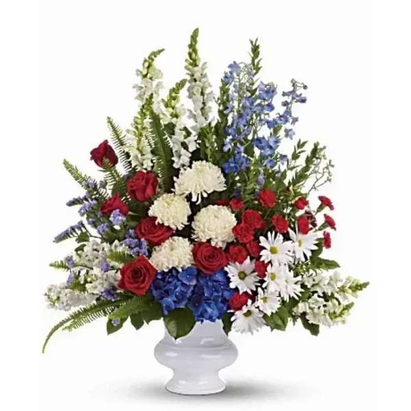 Red roses, white flowers, and blue blooms in a white vase