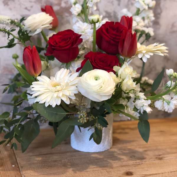 Red and white mixed flower arrangement in a white vase