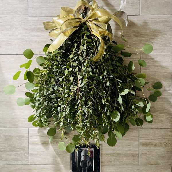 Hanging greenery arrangement with a gold ribbon bow