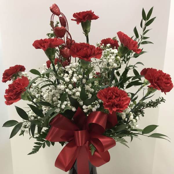 Red carnations in a black vase with a red ribbon bow