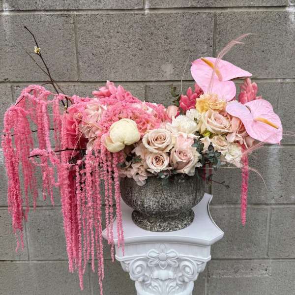 Pink floral arrangement in a stone urn with cascading blooms
