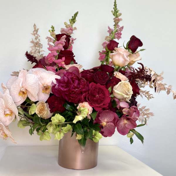 Pink and burgundy floral arrangement in a metallic vase