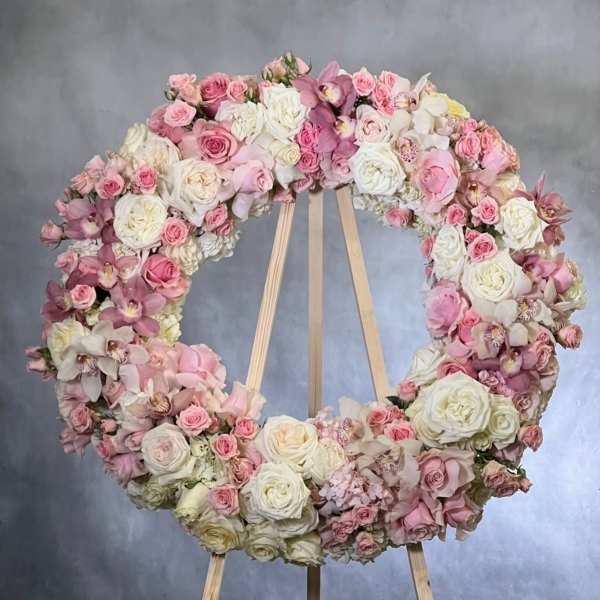 Circular floral wreath of pink and white roses on a wooden easel