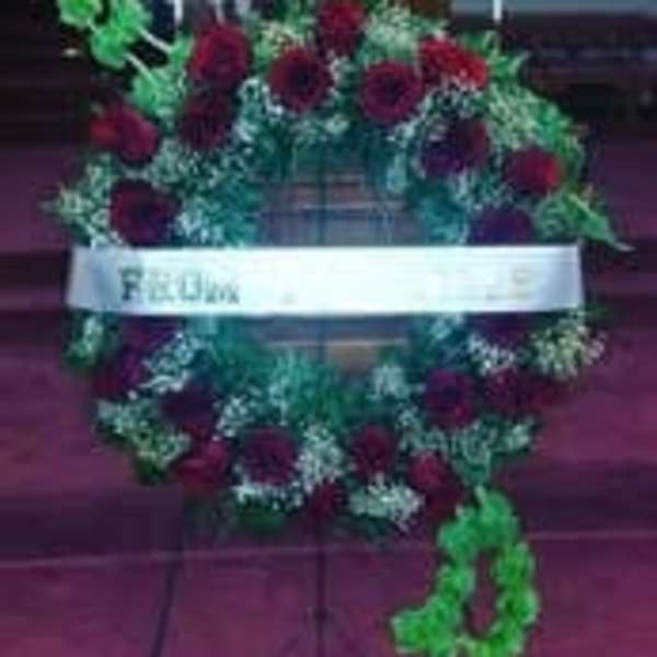 Heart-shaped floral wreath with red roses and a white ribbon