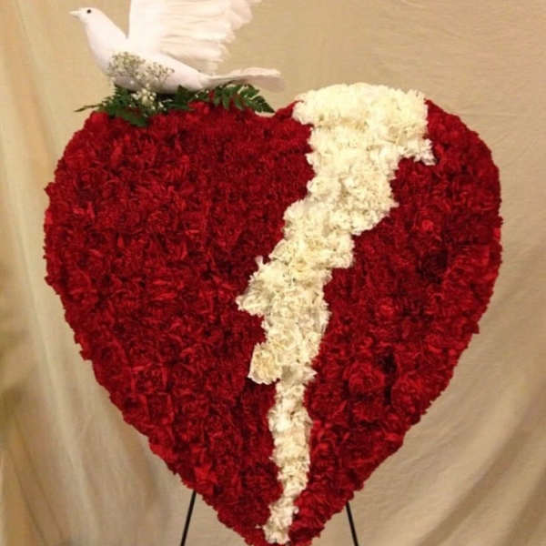 Heart-shaped red floral tribute with a white dove and white ribbon