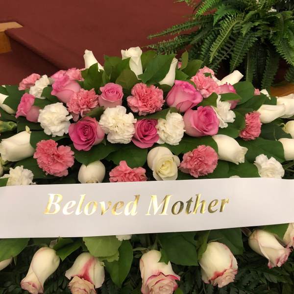 Pink and white floral spray with a "Beloved Mother" ribbon