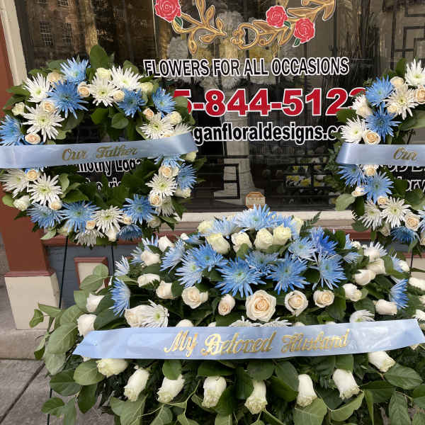 Three blue and white floral wreaths with memorial ribbons
