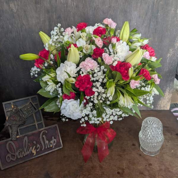 Bouquet of pink, white, and red flowers in a glass vase with a red ribbon