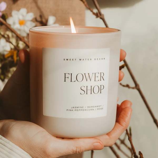 Lit flower shop candle in a frosted glass jar