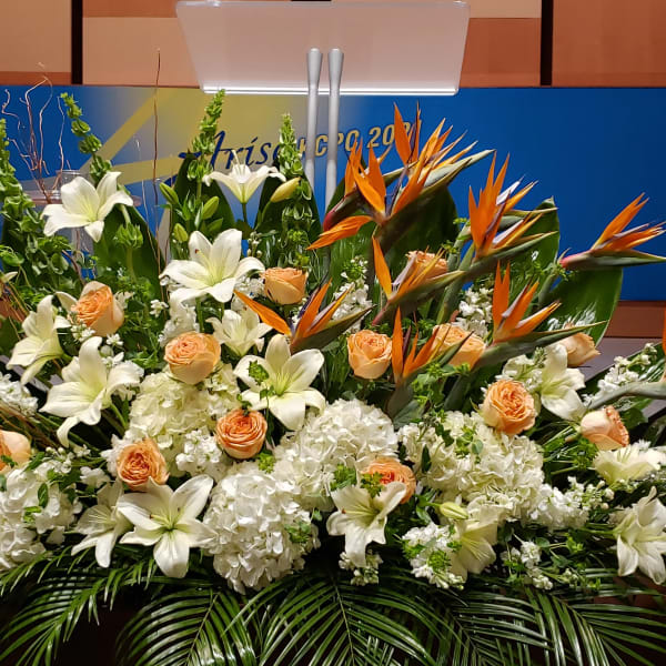 Large stage arrangement of white lilies, peach roses, Birds of Paradise, and white hydrangeas