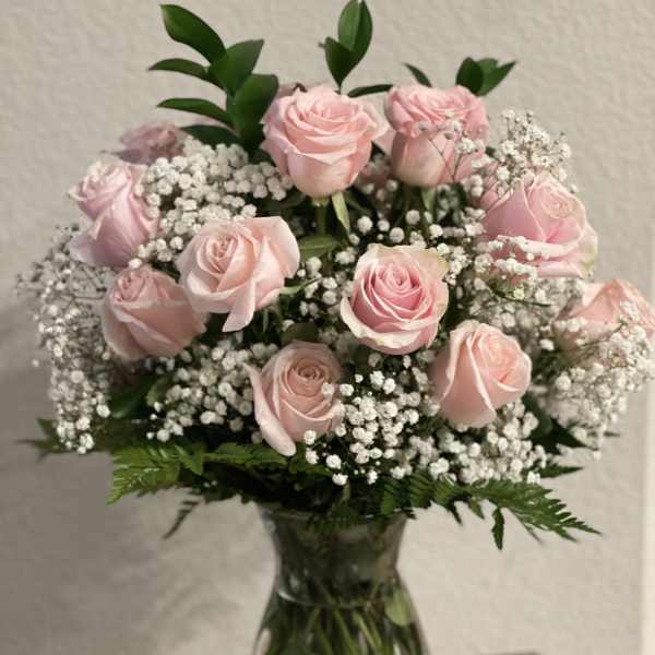 Pink roses arranged in a clear glass vase with baby's breath