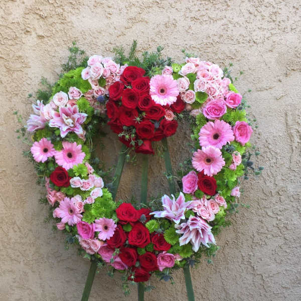 Heart-shaped floral wreath with red and pink roses and pink daisies