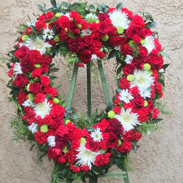 Heart-shaped floral wreath with red roses, red carnations, and white daisies