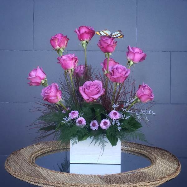 Pink roses arranged in a white box with small pink filler flowers