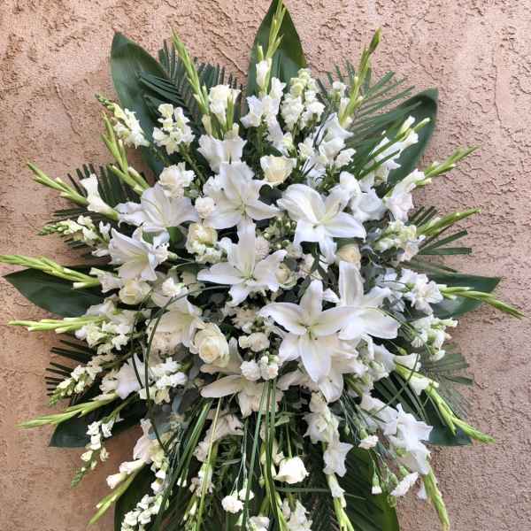 White lily and snapdragon floral spray with dark green foliage