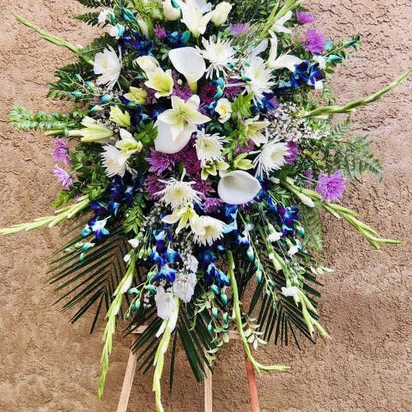 Large standing floral spray with white lilies, calla lilies, and purple blooms