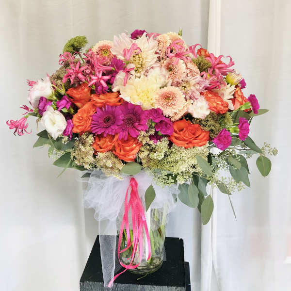 Large bouquet of pink, orange, and white flowers in a glass vase