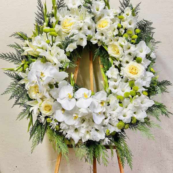 White floral wreath on a wooden easel with orchids and roses