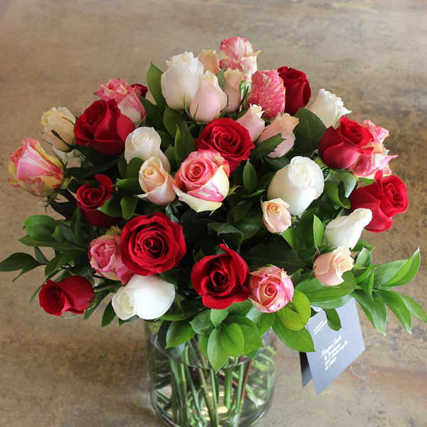 Mixed roses in a clear glass vase.