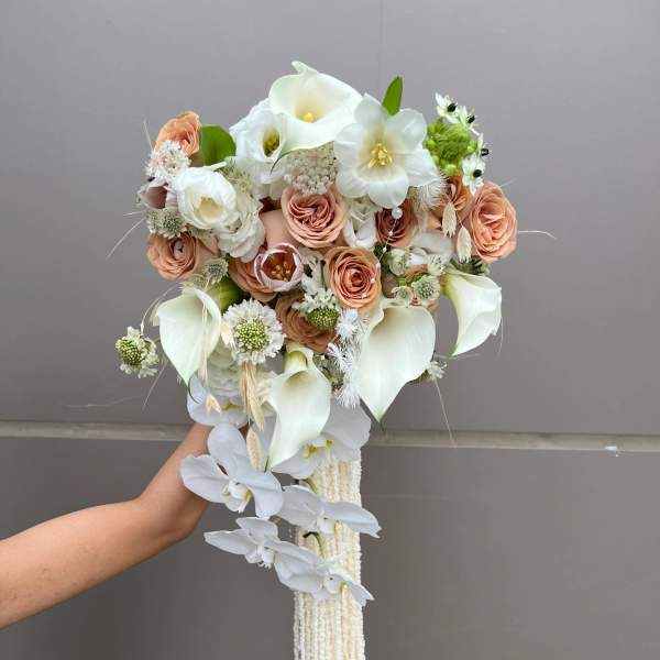 Handheld bouquet with white calla lilies, peach roses, and trailing white orchids