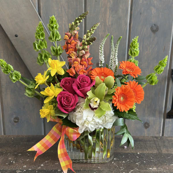 Colorful mixed bouquet in a clear glass vase with a plaid ribbon