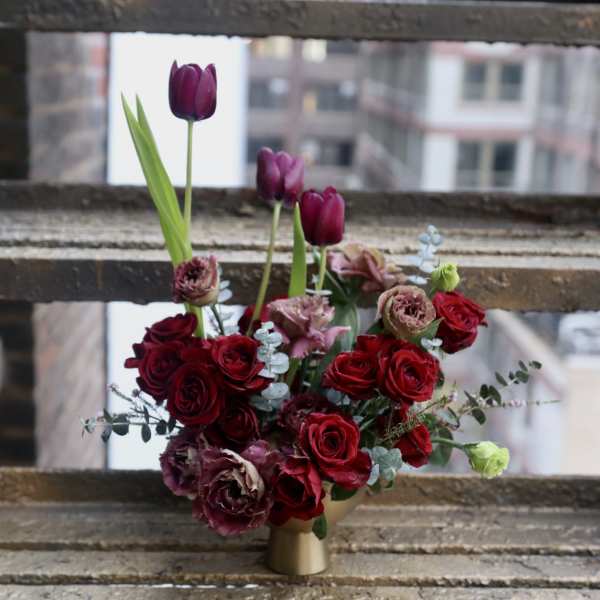 Bouquet of red roses and purple tulips in a gold vase