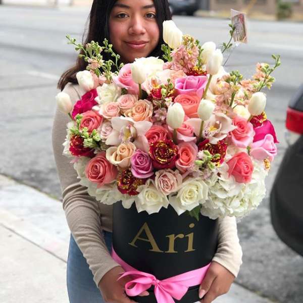 Woman holding a large bouquet of pink and white roses in a black box