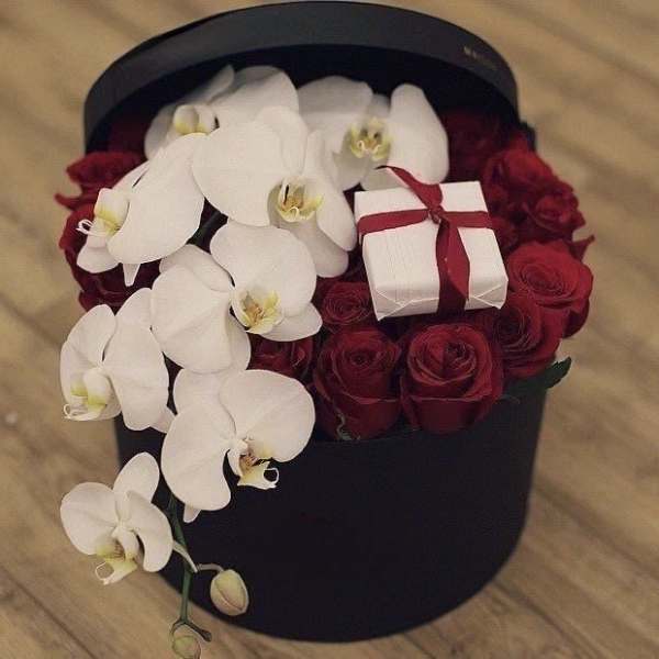 Black hatbox with white orchids, red roses, and a small gift box