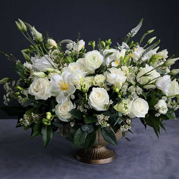 Large white floral arrangement in a bronze pedestal vase