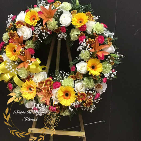 Heart-shaped floral wreath with yellow gerberas, white roses, and orange lilies