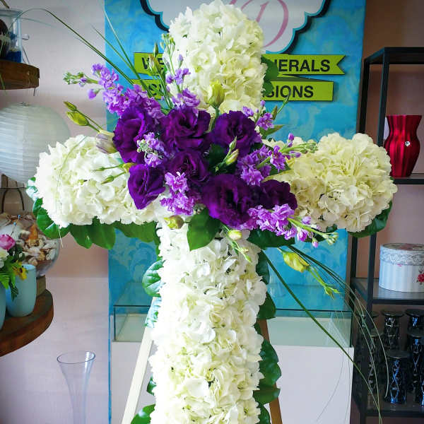 Cross-shaped floral tribute with white hydrangeas and purple lisianthus