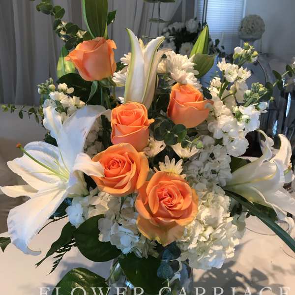 Orange roses and white lilies in a glass vase