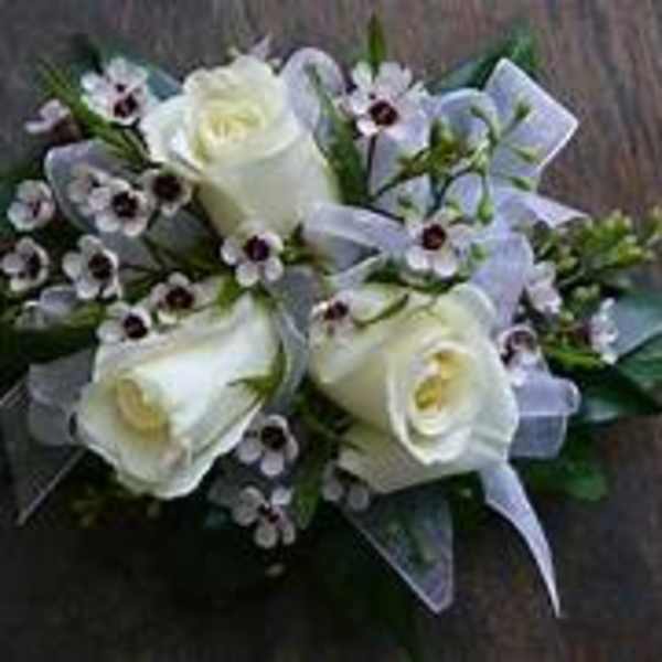 White roses and small purple flowers arranged with a ribbon