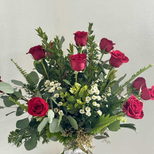 Bouquet of red roses and small white flowers in a clear glass vase