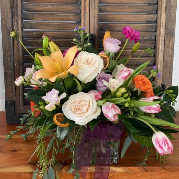 Mixed bouquet with roses, lilies, and tulips in a glass vase