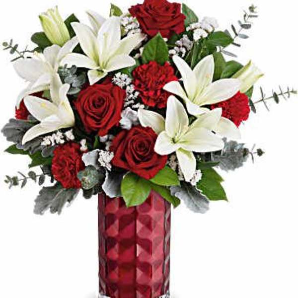 Red roses and white lilies arranged in a red glass vase
