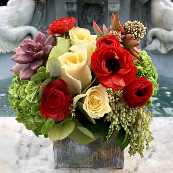 Bouquet of red and cream roses with succulents in a wooden box