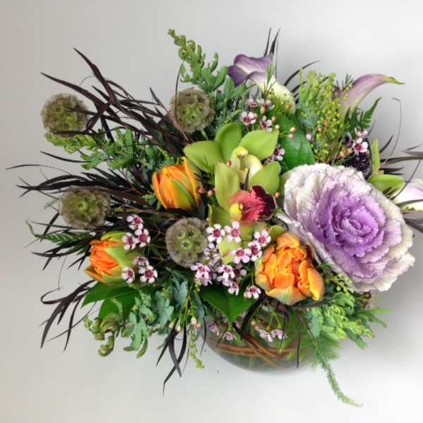 Mixed bouquet with purple cabbage roses and orange tulips in a low vase