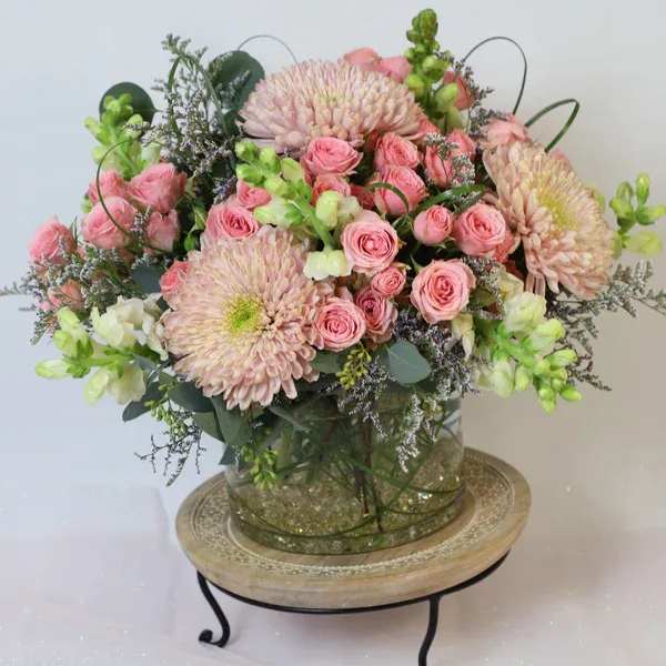 Pink roses and pale chrysanthemums arranged in a glass vase